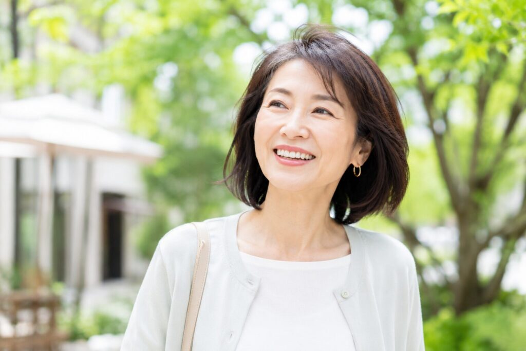50代女性が外で楽しそうに笑っている