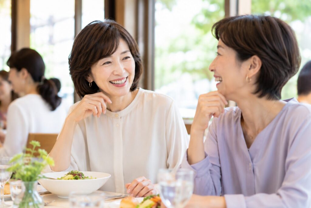 友人とレストランで談笑する50代女性
