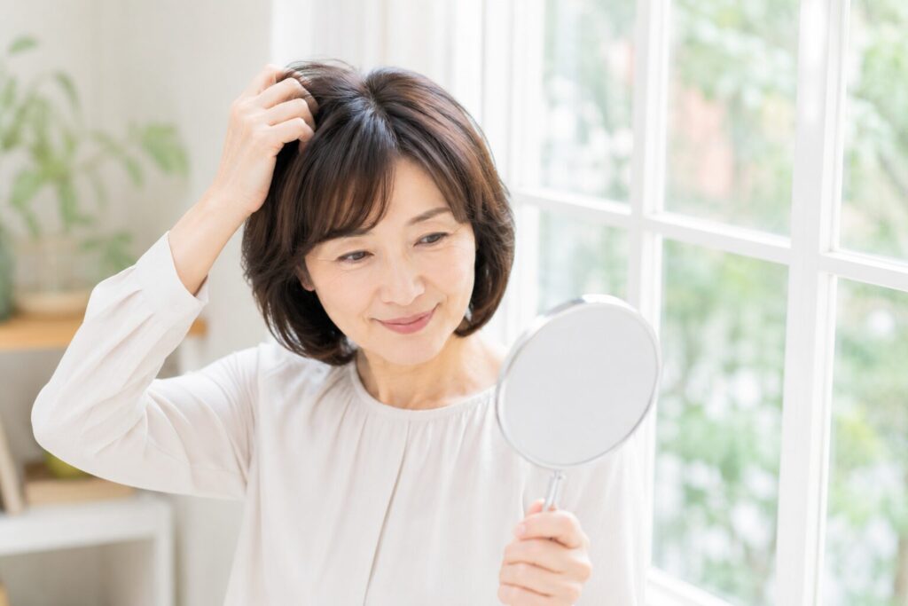 窓辺で髪をチェックしている女性